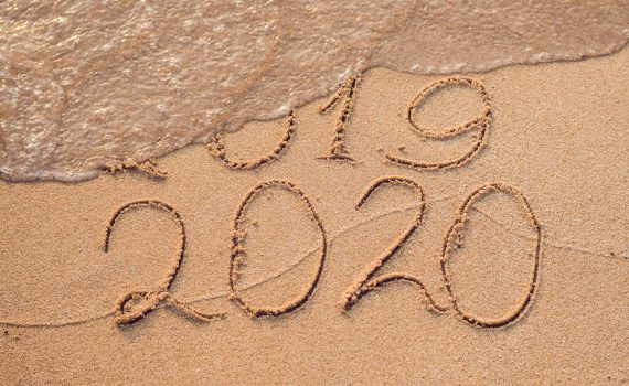 New Year 2020 is coming concept - inscription 2019 and 2020 a beach sand, the wave is almost covering the digits 2019.