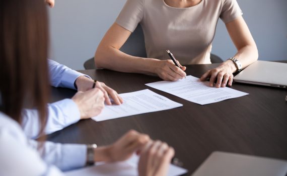 Close up view of new business partners fill document form sign two-sided contract concept, man and woman put written signature on legal document making partnership collaboration or sale purchase deal